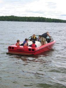 Guests wearing life jackets in a red motorboat on Wabana Lake