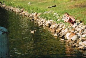Young guest swimming near a rocky shoreline
