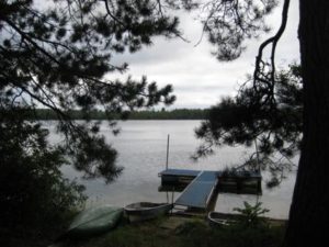 Dock framed by pine branches overlooking Wabana Lake