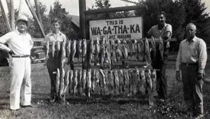 Guests displaying their catch beside the WA‑GA‑THA‑KA Resort sign