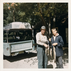 Two people displaying fish beside a vintage Studebaker truck