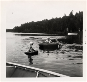 Family swimming with inner tubes on Wabana Lake in July 1958